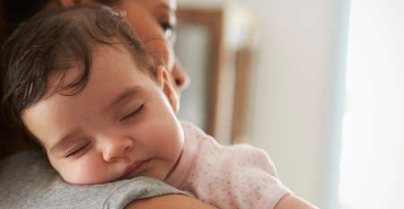 Baby sleeping over mother's shoulder