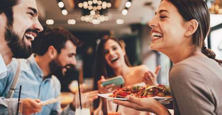 Friends laughing enjoying a meal together