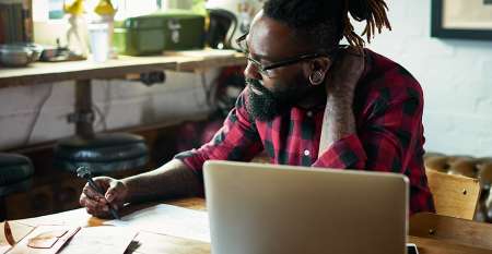 Man with laptop writing notes