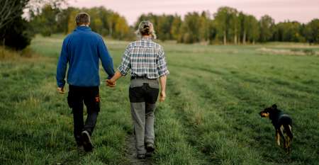Man, woman and dog walking in field