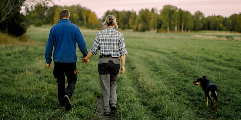 Dyn, menyw a chi yn cerdded yn y cae