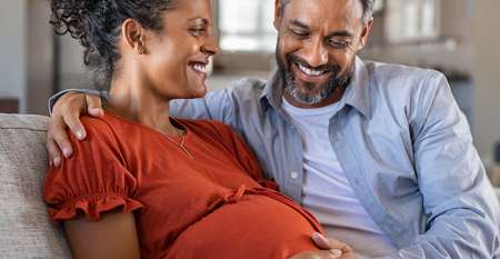 Pregnant mother with partner touching her belly