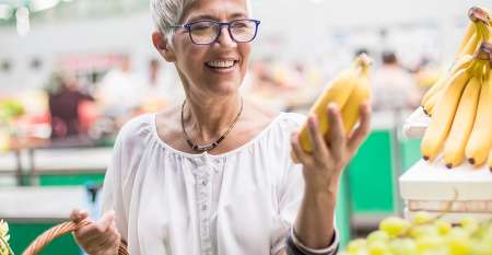 Senior woman choosing bananas to buy Senior woman choosing bananas to buy