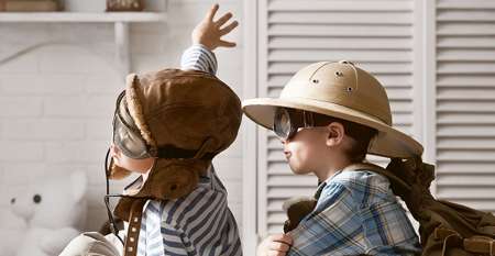 Two young boys dressing up playing aeroplane using a suitcase
