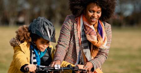Woman helping child ride bike Woman helping child ride bike