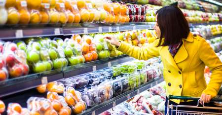 Woman in supermarket holding trolley selecting food Woman in supermarket holding trolley selecting food
