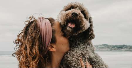 Woman on beach hugging dog