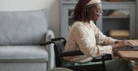 Woman sitting in a wheelchair using laptop
