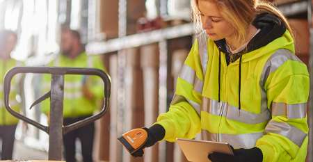 Woman wearing hi vis jacket checking stock in warehouse