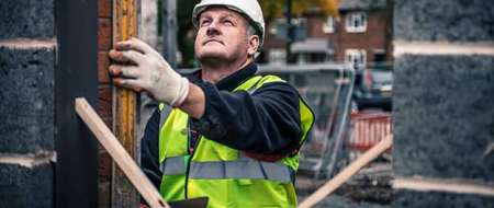 Builder using spirit level on a wall