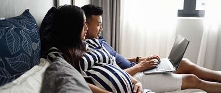 Man and pregnant woman sitting on sofa