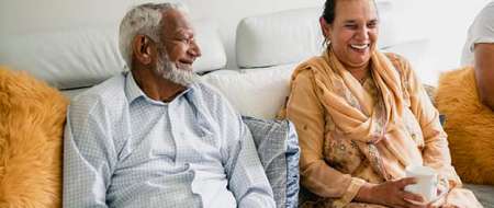 Older couple sitting on sofa laughing