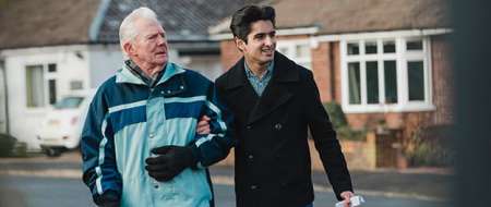 Older man and young man walking arm in arm