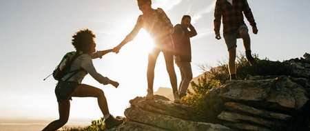 People helping each other climb hillside