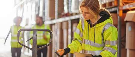 Woman wearing hi vis jacket checking stock in warehouse