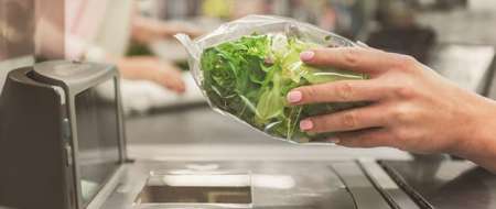 Womans hand scanning pack of salad at self serve-checkout