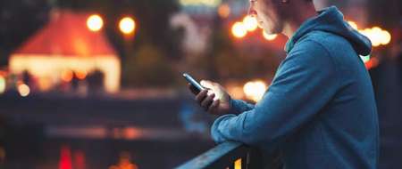 Young man at night looking at his phone 