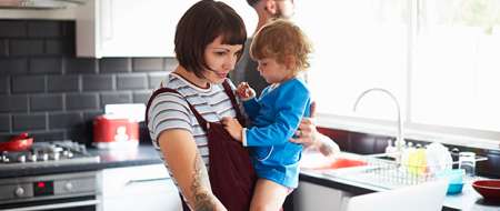 Parents in kitchen, mother holding young child