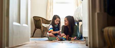 Woman lying on the floor playing with young girl