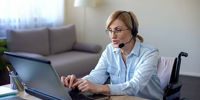 Menyw yn gwisgo clustffonau yn ffonio ar gyfrifiadur